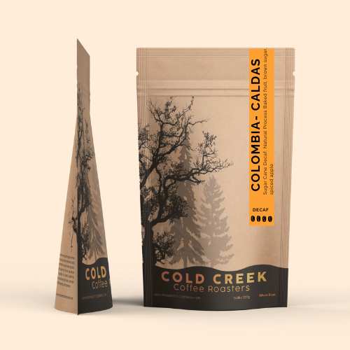 Cold Creek Coffee Roasters Colombia Caldas Decaf coffee pouch with forest design and vertical orange label.